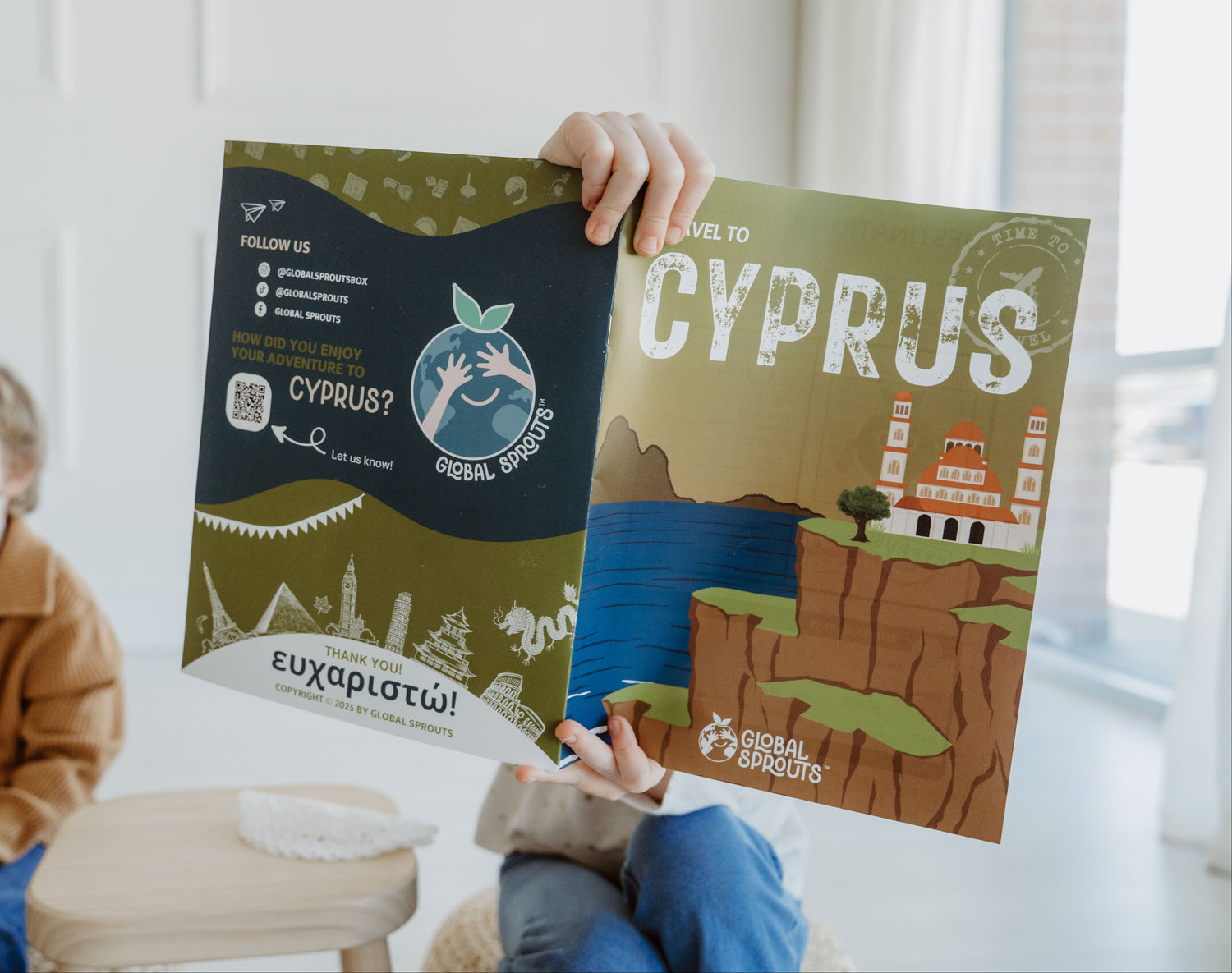 Child holding a travel guidebook about Cyprus in a bright room.