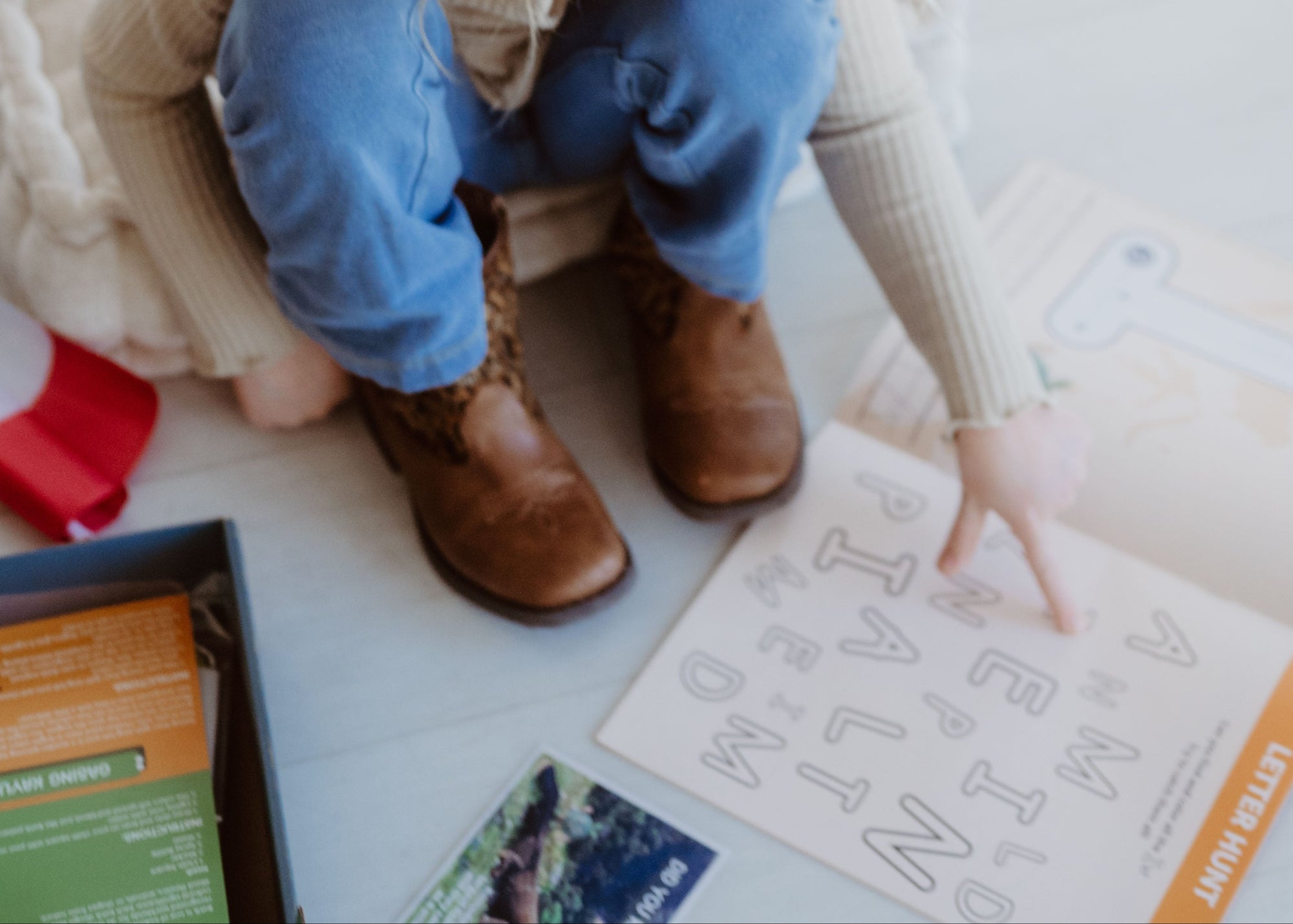 Child sitting on a white floor with educational materials